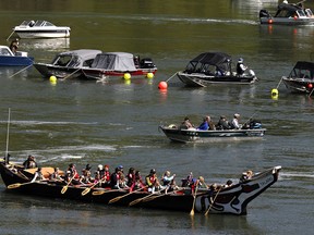 In this May 4, 2011 file photo, a group of people in a large canoe head upriver into scores of fishing boats during the Spring Chinook Salmon run on the Willamette River in Oregon City, Ore. Federal officials are considering putting a once-flourishing West Coast salmon on the list of threatened or endangered species. The National Marine Fisheries Services said Tuesday, Feb. 27, 2018, it will investigate whether to give protected status to spring-run Chinook salmon in and around the Klamath River.