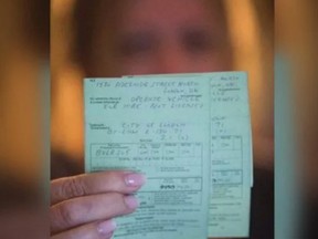 A woman holds two citations totalling $2,260 in fines she received after driving patients to the hospital in London.