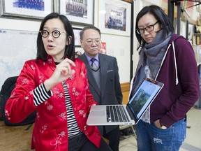 June Chow (L) and her sister Doris Chow (R) look at images from their trip to Kaiping with Peter Woo of the Hoy Ping Benevolent Association,  Vancouver, February 08 2018.