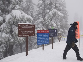 A park rangers stands at the tail head of a popular hiking trail on Mount Seymour in North Vancouver, B.C., Thursday, Feb. 1, 2018. Police say two men have been taken to hospital following apparent "criminal actions" on top of the mountain.