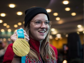 Freestyle-skier Cassie Sharpe of Comox holds her Olympic gold medal after arriving from South Korea at Vancouver airport in Richmond on Feb. 26.