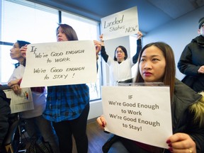 Caregivers and supporters hold up signs as they listen to speakers during a news conference at the B.C. Federation of Labour office in Vancouver on Feb. 12, 2018.