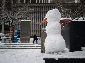 A man walks past a snowman on a bench outside an office tower in downtown Vancouver, B.C., on Friday February 23, 2018. Environment Canada issued a snowfall warning for Metro Vancouver with 10 to 20 centimetres of snow expected. The warning has since been lifted.