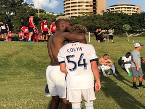 Kendall Waston gives 15-year-old Whitecaps Residency player Simon Colyn a hug after he made his first team debut in Hawaii.