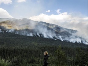 A women stops on the side of the highway to watch a forest fire burn near Revelstoke B.C. on Saturday August 19, 2017.