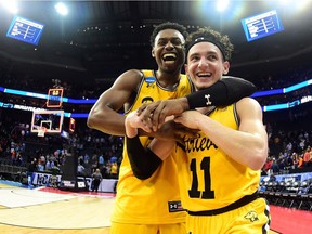 K.J. Maura #11 and teammate Jourdan Grant #5 of the UMBC Retrievers celebrate their 74-54 victory over the Virginia Cavaliers during the first round of the 2018 NCAA Men's Basketball Tournament at Spectrum Center on March 16, 2018 in Charlotte, North Carolina.