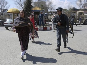 An Afghan woman cries as she runs near the site of a suicide attack in front of Kabul University, in Kabul, Afghanistan, Wednesday, March 21, 2018.