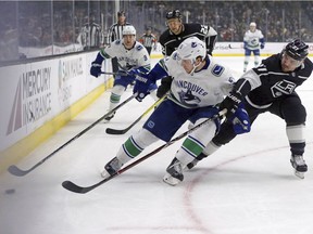 Vancouver Canucks defenseman Derrick Pouliot (5) and Los Angeles Kings defenseman Alec Martinez (27) battle in the first period of an NHL hockey game in Los Angeles, Monday, March 12, 2018.
