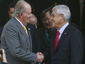 Spain's emeritus King Juan Carlos, left, shakes hands with Chile's President-elect Sebastian Pinera, after their meeting at the Academia Diplomatica de Chile, in Santiago, Saturday, March 10, 2018.