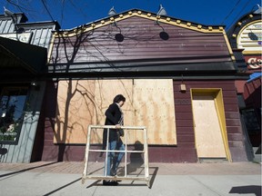 A woman walks past a boarded-up property on Glover Road owned by developer Eric Woodward in Fort Langley. He has six buildings boarded up on the village's main street, worrying people who rely on the tourist trade for their income.