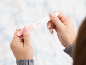 In this stock photo, a woman holds a pregnancy test.