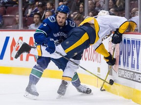 Vancouver Canucks' Derrick Pouliot, left, checks Nashville Predators' Nick Bonino during first period NHL hockey action in Vancouver on Friday, March 2, 2018.