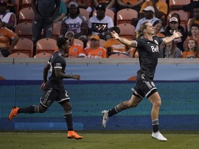 Vancouver Whitecaps's Brek Shea, right, celebrates with Yordy Reyna, left, after scoring against the Houston Dynamo Saturday, in Houston.