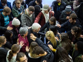 Trinity Western University President, Bob Kuhn, is surrounded by students and faculty during a prayer circle at the campus in Langley, British Columbia on November 21, 2017.