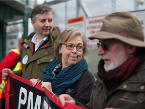 Federal Green Party Leader Elizabeth May, centre, and NDP MP Kennedy Stewart, left, stand with protesters before they were arrested outside Kinder Morgan's facility in Burnaby, B.C., on Friday March 23, 2018.