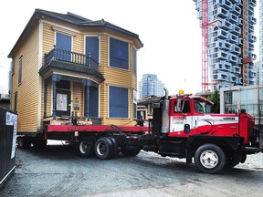 Historic Leslie House, known as the "Little Yellow House", is relocated to a spot across the lane from its current home at Hornby and Pacific, with Vancouver House in the background.