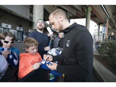 Vancouver Canucks Alexander Edler signs a jersey for Harrison Kobos prior to their NHL game against the Columbus Blue Jackets in Vancouver, BC, March, 31, 2018.