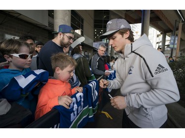 Vancouver Canucks Jake Virtanen signs a jersey for Harrison Kobos (centre) and his brother Zach prior to their NHL game against the Columbus Blue Jackets in Vancouver, BC, March, 31, 2018.
