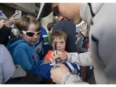 Harrison Kobos (centre) looks on as Vancouver Canucks Jake Virtanen signs a jersey for his brother Zach prior to their NHL game against the Columbus Blue Jackets in Vancouver, BC, March, 31, 2018.