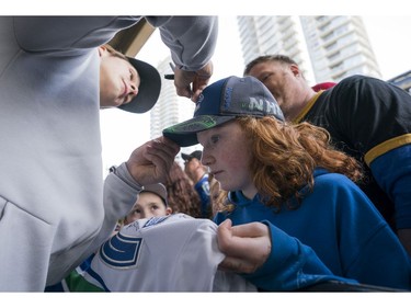 Vancouver Canucks fan Lily Carlos gets her hat signed by Vancouver Canucks Jake Virtanen prior to their NHL game against the Columbus Blue Jackets in Vancouver, BC, March, 31, 2018.
