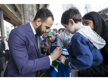 Vancouver Canucks Darren Archibald signs a jersey for a young fan prior to their NHL game against the Columbus Blue Jackets in Vancouver, BC, March, 31, 2018.