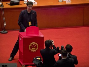 A staff member stands in front of a ballot box on the rostrum before a plenary session of China's National People's Congress (NPC) at the Great Hall of the People in Beijing, Sunday, March 11, 2018. China's top legislative body is expected to approve an amendment too China's constitution on Sunday that will abolish term limits on the presidency and enable Chinese President Xi Jinping to rule indefinitely.