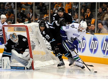 MAY 20:  Daniel Sedin #22 of the Vancouver Canucks brings the puck from behind the net around Joe Thornton #19 and Douglas Murray #3 of the San Jose Sharks in the second period in Game Three of the Western Conference Finals in San Jose, California. The Sharks defeated the Canucks 4-3.