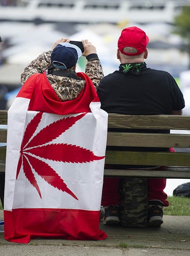 A man wearing a cannabis flag takes a photo at Sunset Beach during the annual 4/20 protest in Vancouver.