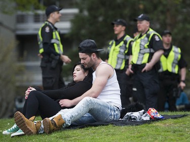 A couple enjoys a quiet moment at Sunset Beach as police watch the annual 4/20 protest in Vancouver.