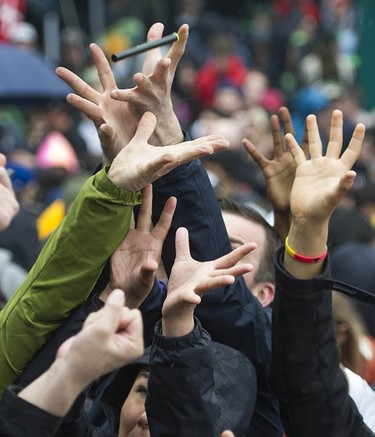 Hands reach out for free cannabis products tossed to the crowd gathered at Sunset Beach for the annual 4/20 protest in Vancouver.