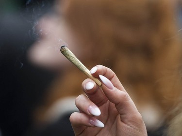 A woman holds a joint as cannabis enthusiasts gather at Sunset Beach for the annual 4/20 protest in Vancouver.