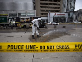 A hazmat worker scrubs the sidewalk of blood and debris in an outline of where a body laid after a mass killing on Yonge St. at Finch Ave. on April 24, 2018 in Toronto, Canada.