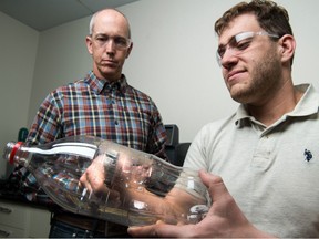 Researchers Bryon Donohoe and Nic Rorrer at the National Renewable Energy Laboratory (NREL) punching out coupon samples from a plastic bottle.