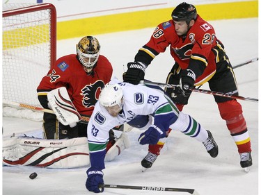 Dec. 01, 2010: From left, the Calgary Flames' Miikka Kiprusoff watches the puck as the Vancouver Canucks' Henrik Sedin is knocked to the ice by Robyn Regehr during first period of their NHL game at the Scotiabank Saddledome in Calgary, Alberta.
