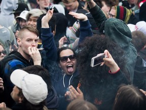 A woman reacts while smoking a joint along with thousands of others during the 4-20 annual marijuana celebration, in Vancouver, B.C., on Friday April 20, 2018.