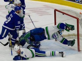 Utica Comets goalie Thatcher Demko tries to dive and make the save behind Comets defenceman Dylan Blujus, on ice, and the Marlies' Ben Smith, left, on April 22 in Toronto.