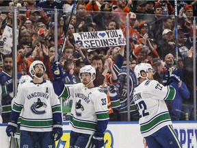 Retiring Vancouver Canucks' Henrik Sedin, centre, and Daniel Sedin, right, acknowledge the crowd as they cheer for them during a break against the Edmonton Oilers in Edmonton on Saturday night. The OIleres won 3-2 in a shootout.