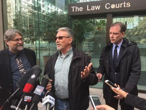 David Trapp, who is the representative plaintiff in a class-action suit aimed at stopping partisan, B.C. government advertising, talks to reporters April 13 outside the Vancouver Law Courts. His lawyers, David Fai, left, and Paul Doroshenko, stand by his side.