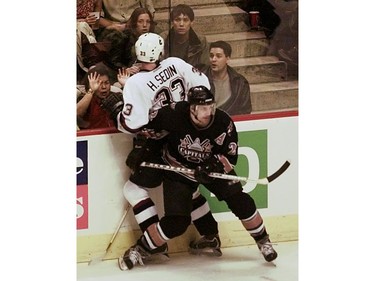 Feb. 14, 2001: Henrik Sedin (33) is pasted against the glass by Washington Capitals winger Steve Konowalchuk (22) during the second period of NHL action at GM Place.
