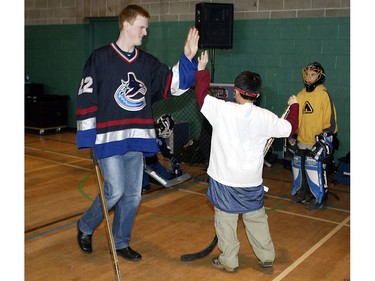 Mar. 03, 2002: Daniel Sedin congratulates one of the children participating in the NHL Street Program at the Fraserview Boys and Girls Club . This event featured a coaching clinic by Marc Crawford, and skill sessions by Henrik and Daniel Sedin, as well as entertainment by Canucks mascot Fin.  The Canucks NHL Street Program provides street hockey equipment to local community centres and youth programs in order to provide greater access and participation in hockey to those kids, aged 6-16, who would not otherwise get the opportunity to play.