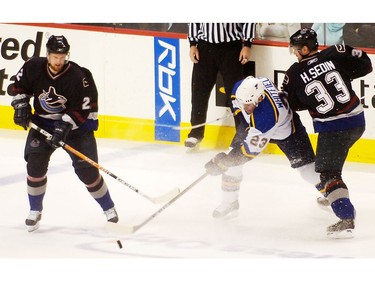 Mar. 5, 2006: Daniel and Henrik battle for the puck with  St. Louis Blues' Trent Whitfield (23) during NHL first period regular season action at GM Place