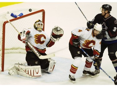 Apr. 19, 2004: Henrik Sedin  (#33) watches the puck go flying over the net above Calgary Flames' goalie Mikka Kiprusoff (#34) as he's checked by defenceman Jordan Leopold (#4) during game seven's third period of the first round of the NHL's Western Conference 2004 Stanley Cup playoffs at GM Place