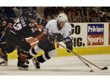 Sept. 25, 2001: Henrik Sedin (#33) tries to stick handle his way past Calgary Flames defenseman Toni Lydman (#32) during a NHL pre-season exhibition game in Vancouver at GM Place.