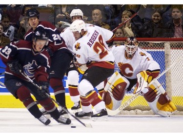 Oct. 14, 2002: Trent Klatt (#26, left) watches teammate Henrik Sedin (#33) gather up a loose puck as Calgary Flames Robyn Regehr (#28) and goalie Roman Turek (#1) guard the net during the first period of a NHL regular season game at GM Place.