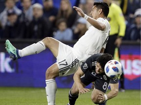 Sporting Kansas City midfielder Roger Espinoza (17) and Vancouver Whitecaps midfielder Felipe Martins (8) battle for the ball during the first half of an MLS soccer match in Kansas City, Kan., Friday, April 20, 2018.