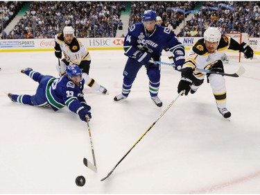 JUNE 1, 2011 -- Vancouver Canucks Henrik Sedin (L) and teammate Alexandre Burrows (2nd R) battle for the puck with Boston Bruins Gregory Campbell and Andrew Ference (R) during the first period of game one