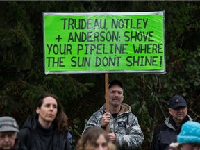 A man holds a sign while listening as other protesters opposed to the Kinder Morgan Trans Mountain pipeline extension defy a court order and block an entrance to the company's property, in Burnaby, B.C., on Saturday April 7, 2018. The pipeline is set to increase the capacity of oil products flowing from Alberta to the B.C. coast to 890,000 barrels from 300,000 barrels.