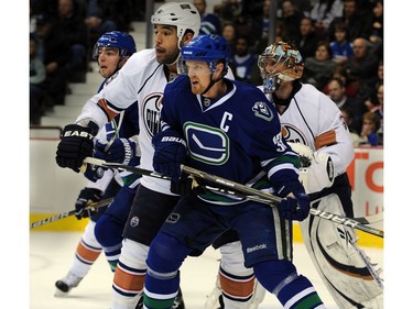 January 7, 2011: Vancouver Canucks Henrik Sedin and Alex Burrows wait for a shot with  Edmonton Oilers Theo Peckham in front of goalie Nikolai Khabibulin.