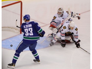 APRIL 13, 2011: Henrik Sedin (left) swings and misses a flying puck for an open net chance as Chicago Blackhawks goalie Corey Crawford (center) and Brent Seabrook (right) get tied up during the third period of game one in the NHL Western Conference quarter final at Rogers Arena.