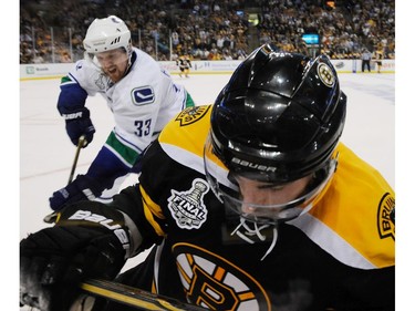 JUNE 13, 2011 -- Vancouver Canucks Henrik Sedin (left) checks Boston Bruins Brad Marchand (right) along the boards during the third period of game six in the 2011 NHL Stanley Cup final at TD Garden.